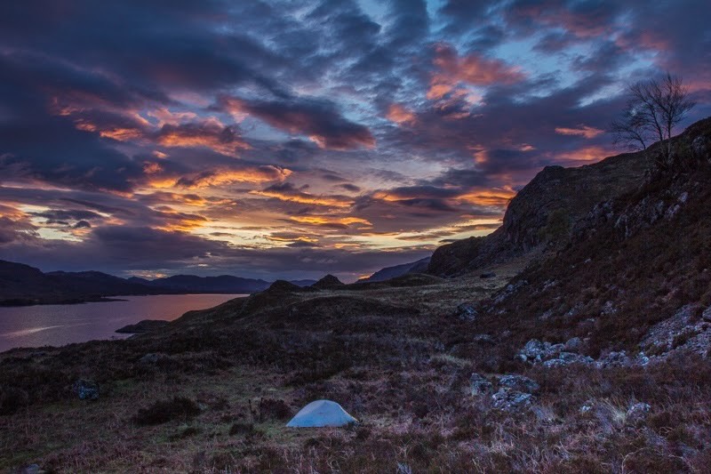Loch Maree mit Zelt mit vom Abendlicht verfärbten Wolken in Schottland
