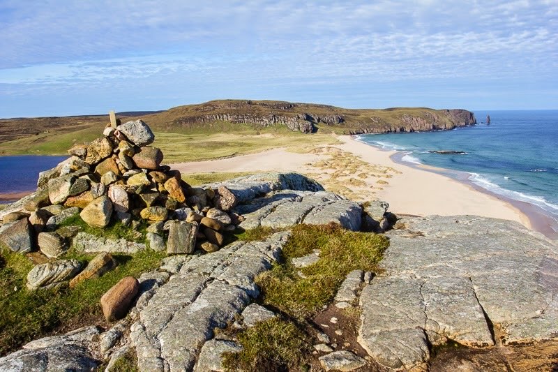 Blick über den Stand und das Beer der Sandwood Bay mit Steinpyramide im Vordergrund in Schottland