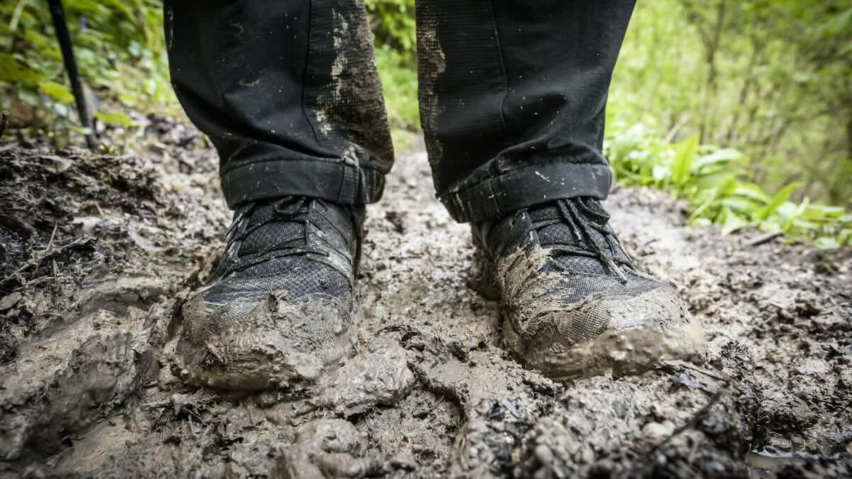 Trailrunning Schuhe eines Wanderers auf einem matschigen Waldweg