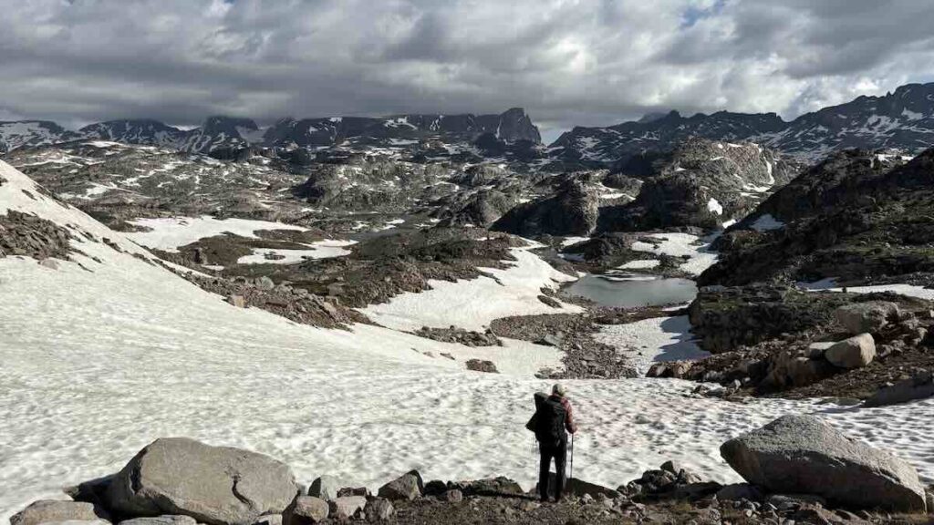 Wanderer vor einer felsigen Landschaft mit Schnee und Seen in den Beartooth Mountains in den USA