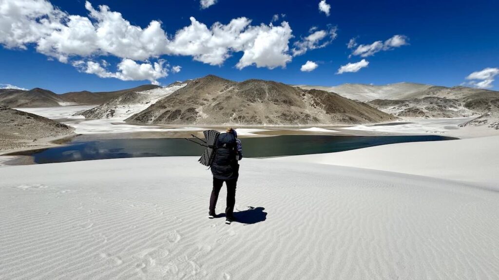 Wanderer vor einer Sandfläche mit einem See und herausragenden Hügeln in Argentinien