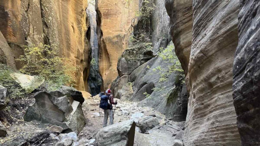 Wanderer in einem Slot canyon mit hohen Felswänden in gelblichem und grauem Farbton in Utah
