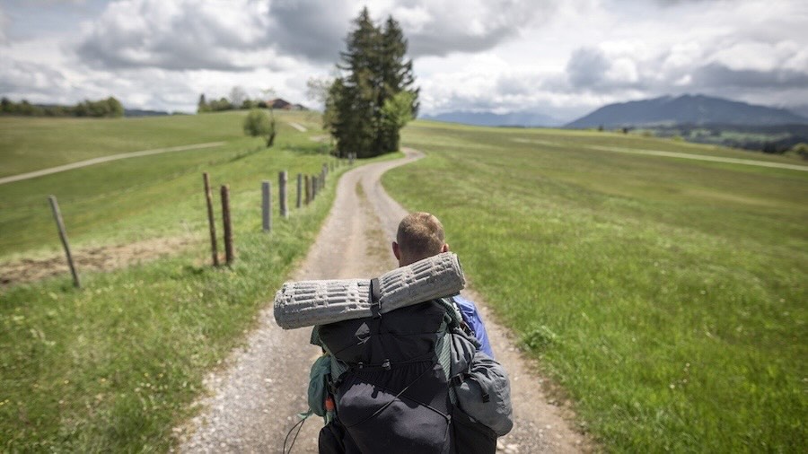 Wanderer von hinten zu sehen läuft auf einem Fahrweg